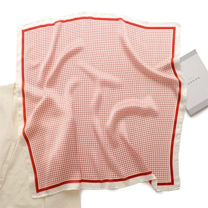 Detailed close-up of red checkered silk scarf with contrast borders and glossy texture