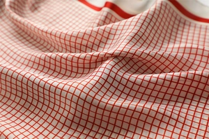 Detail of red and white checkered silk scarf showing soft folds and satin texture