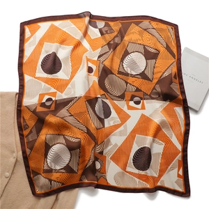 Close-up of geometric abstract printed silk scarf in orange and brown on white background
