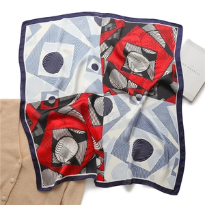 Detailed view of square silk scarf with geometric color block patterns and soft texture