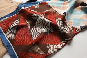 Detail of silk scarf with geometric patterns and bright blue rolled edges on a sweater