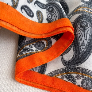 Detailed view of paisley cotton linen scarf with bright orange stitched hem and soft fabric