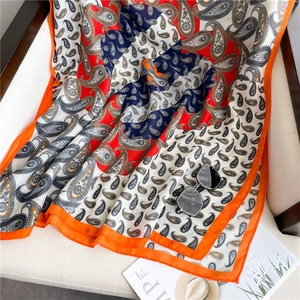 Detail of paisley pattern scarf draped on a chair with sunglasses for a stylish look