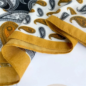 Close-up of lightweight paisley printed scarf with yellow, black and white color blocks