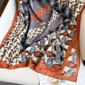 Detail view of large paisley print scarf in silk texture on a neutral chair setting