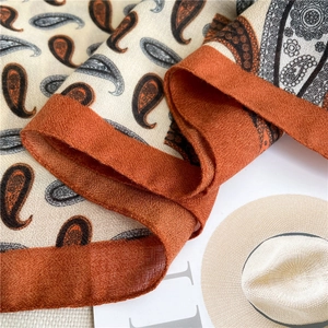 Detailed close-up of paisley pattern cotton linen scarf in burnt orange and grey