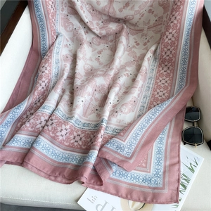 Dettaglio della sciarpa in cotone e lino rosa e beige con motivi etnici e occhiali