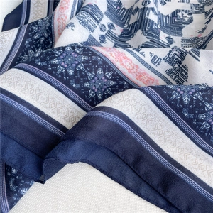 Dettaglio della sciarpa in tessuto leggero con motivi geometrici blu e fiori rosa eleganti