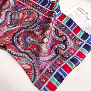 Macro detail of red paisley silk scarf with glossy texture and colorful ethnic patterns