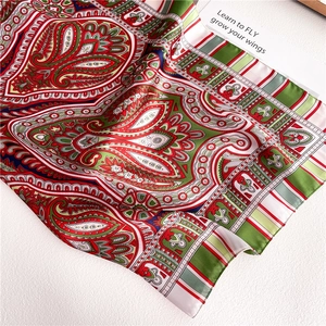 Detailed close-up of paisley print silk scarf with satin finish and vibrant red-green colors