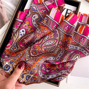 Detail of vibrant paisley silk scarf with magenta and orange patterns in a gift box