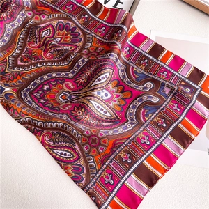 Detailed close-up of paisley pattern on a silky scarf with vibrant magenta and orange tones