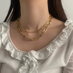 Collana a doppio strato in stile punk dorato per donna su sfondo bianco minimalista