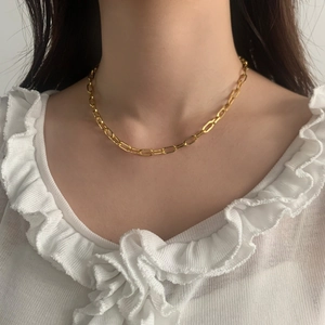 Primo piano di una collana a catena a graffetta dorata minimalista su una modella