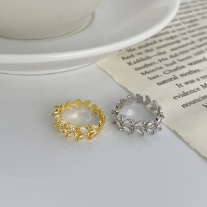Detail of gold and silver leaf rings with marquise-cut cubic zirconia in elegant setting