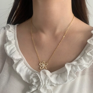 Elegant gold flower necklace with cubic zirconia worn on model with white blouse