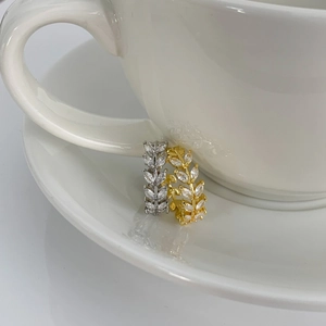 Macro shot of gold and silver leaf rings with cubic zirconia hanging on a ceramic cup