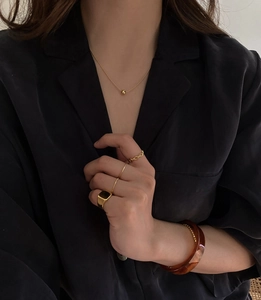 Close-up of vintage gold rings and marble bangle set against a black fabric background