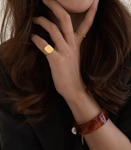 Golden square signet ring paired with tortoise resin bracelet on hand detail