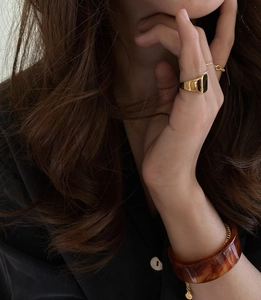 Detail of square gold-plated ring and tortoise shell resin bangle on woman's hand