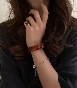 Detail of vintage gold-plated square ring with resin bangle and beaded bracelet on hand