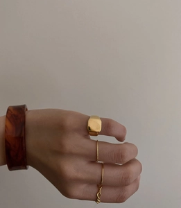 Close-up of gold square signet rings and tortoise resin bangle set for women