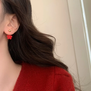 Detail of red flower stud earrings with gold bead on model for a French chic look