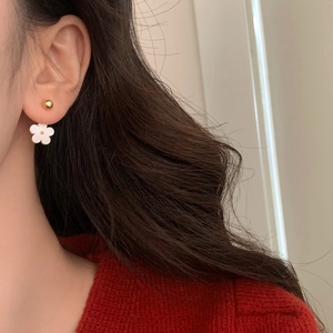 Elegant French gold bead and white flower stud earrings worn on a female ear
