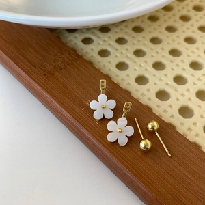 Detail shot of small gold-plated flower stud earrings and round balls on a wood surface
