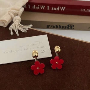 Detailed shot of red five-petal flower drop earrings with elegant gold stud finish