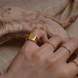 Retro style square gold plated ring set worn on hand with natural wood background