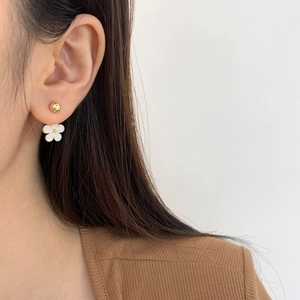 Minimalist white daisy flower stud earrings with gold plating shown on model ear