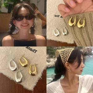 Minimalist gold and silver U-shaped earrings in polished metal on model and still life
