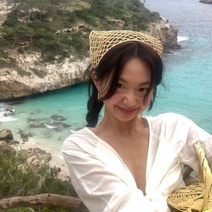 French style crochet headband in beige worn by a model against a scenic beach backdrop