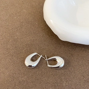 Detailed view of polished silver U-shape hoop earrings on a textured brown surface