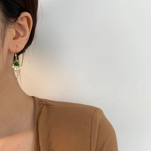 Detail of elegant gold-plated ear hooks with green jade and white freshwater pearls