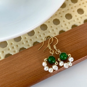 Detail of vintage gold-plated hook earring with green jade bead and freshwater pearls