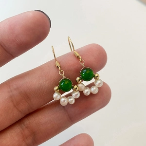Macro view of vintage gold-plated drop earrings with green emerald beads and pearls