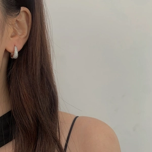 Macro detail of silver hoop earrings featuring micro-paved cubic zirconia on a model