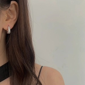 Close-up of silver-plated hoop earrings with micro-pave cubic zirconia on a model ear