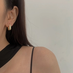 Close-up of elegant gold hoop earrings with micro-pave white zircon stones on a model