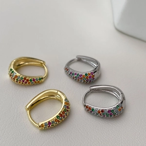 Macro shot of U-shaped gold and silver earrings featuring colorful pavé rainbow zircons