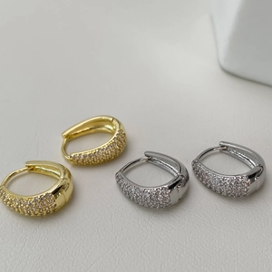 Detailed close-up of gold and silver U-shaped hoop earrings with micro-pave cubic zirconia