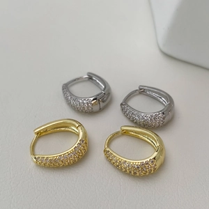 Close-up of gold and silver huggie earrings with pavé white zircon and hinge closure