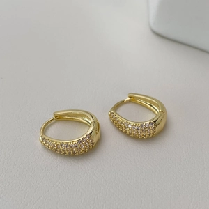 Detailed close-up of gold-plated oval hoop earrings with shimmering pave-set zircon stones
