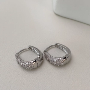Detailed view of silver hoop earrings with micro-pave cubic zirconia on white leather