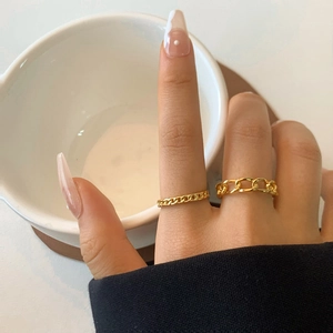 Dettaglio di anelli a catena d'oro spessi e fascia cubana sottile su mano estetica