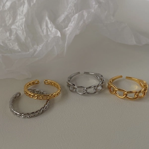 Dettaglio di anelli a catena regolabili in oro e argento dal design minimalista