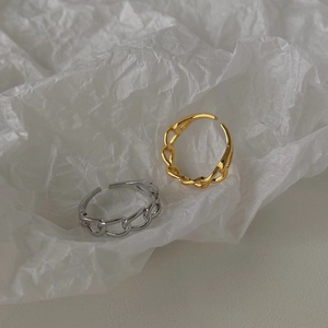 Dettaglio degli anelli a catena regolabili in oro e argento su sfondo di carta ruvida