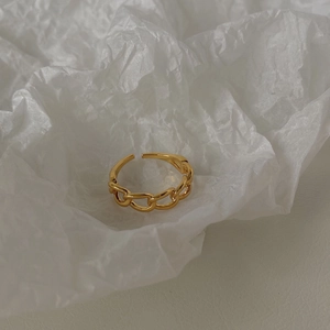 Dettaglio ravvicinato di un anello a maglia a catena dorata su carta bianca artistica